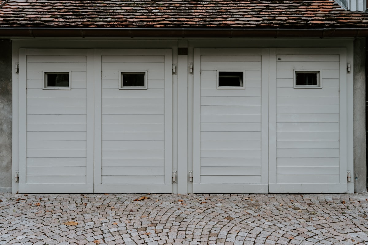 Hinged Carriage-Style Garage Doors with Windows on a Tile-Roofed Garage